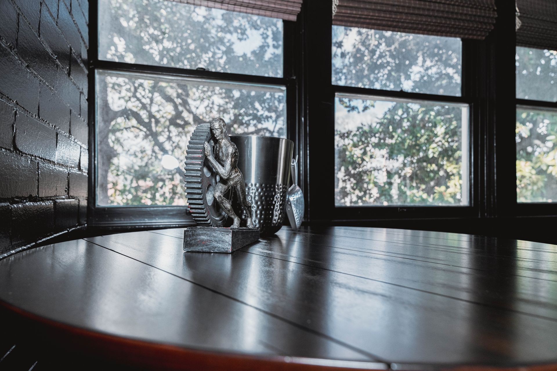 A table with a cup on it in front of a window.