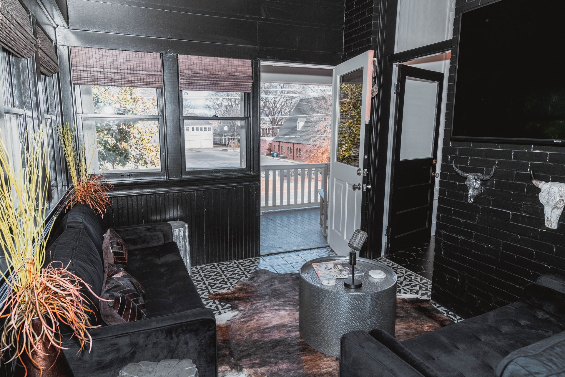 A living room with a black couch and a silver coffee table.