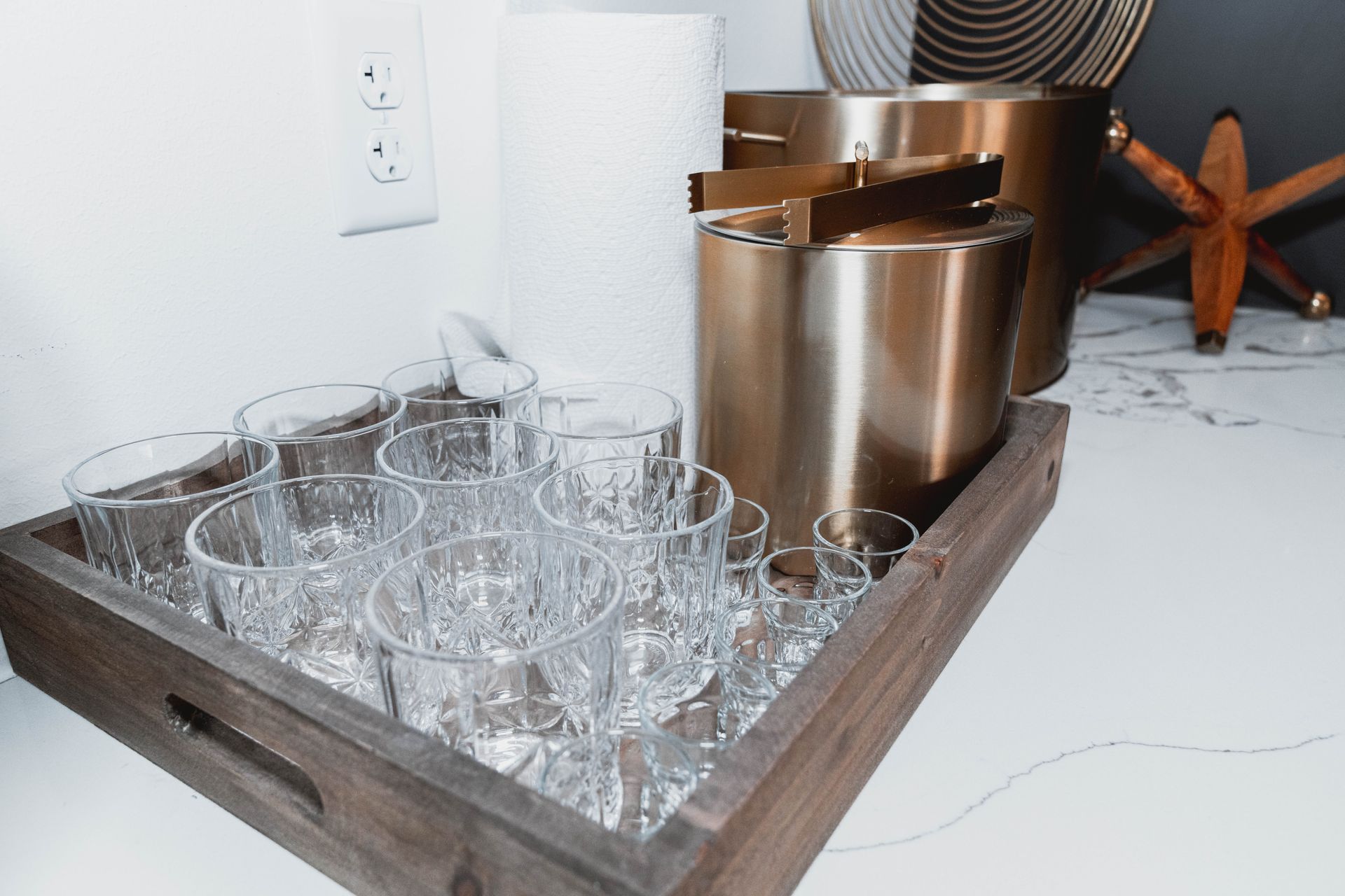 A wooden tray filled with wine glasses and an ice bucket.