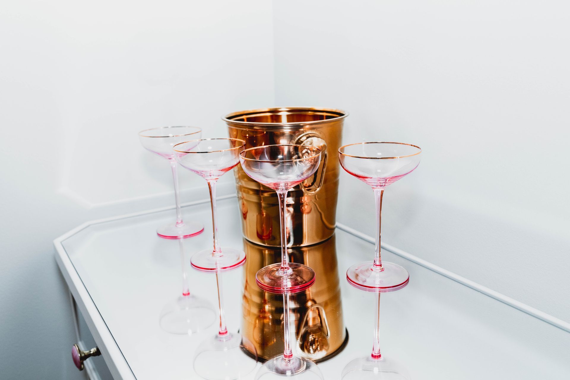 Three champagne glasses and a bucket of ice are on a table.