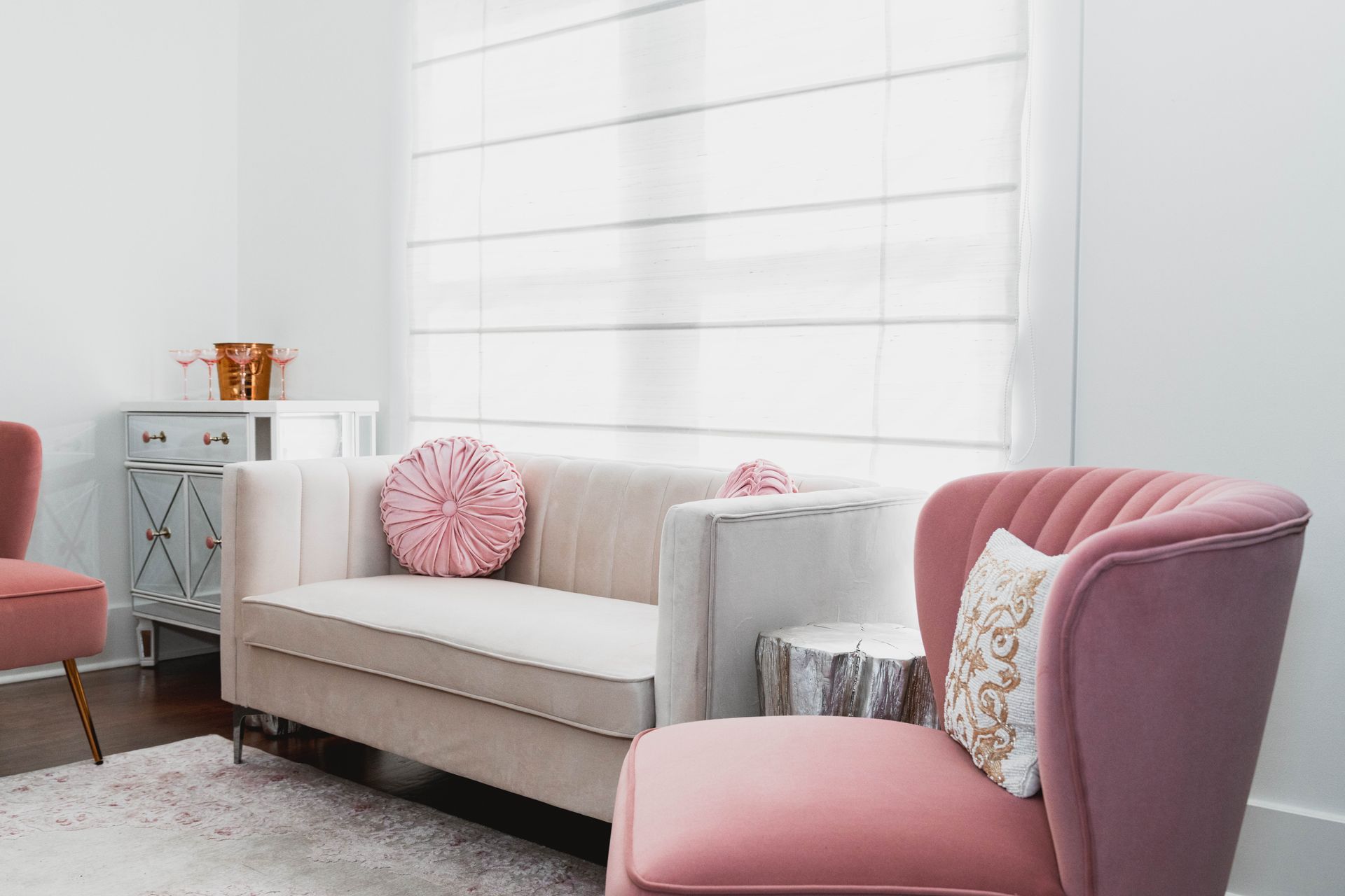 A living room with a couch and two pink chairs.
