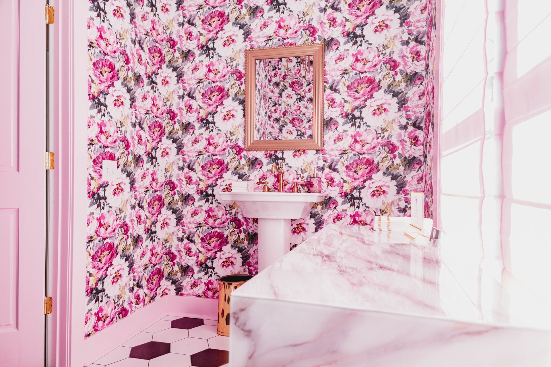 A bathroom with pink walls , a sink , and a mirror.
