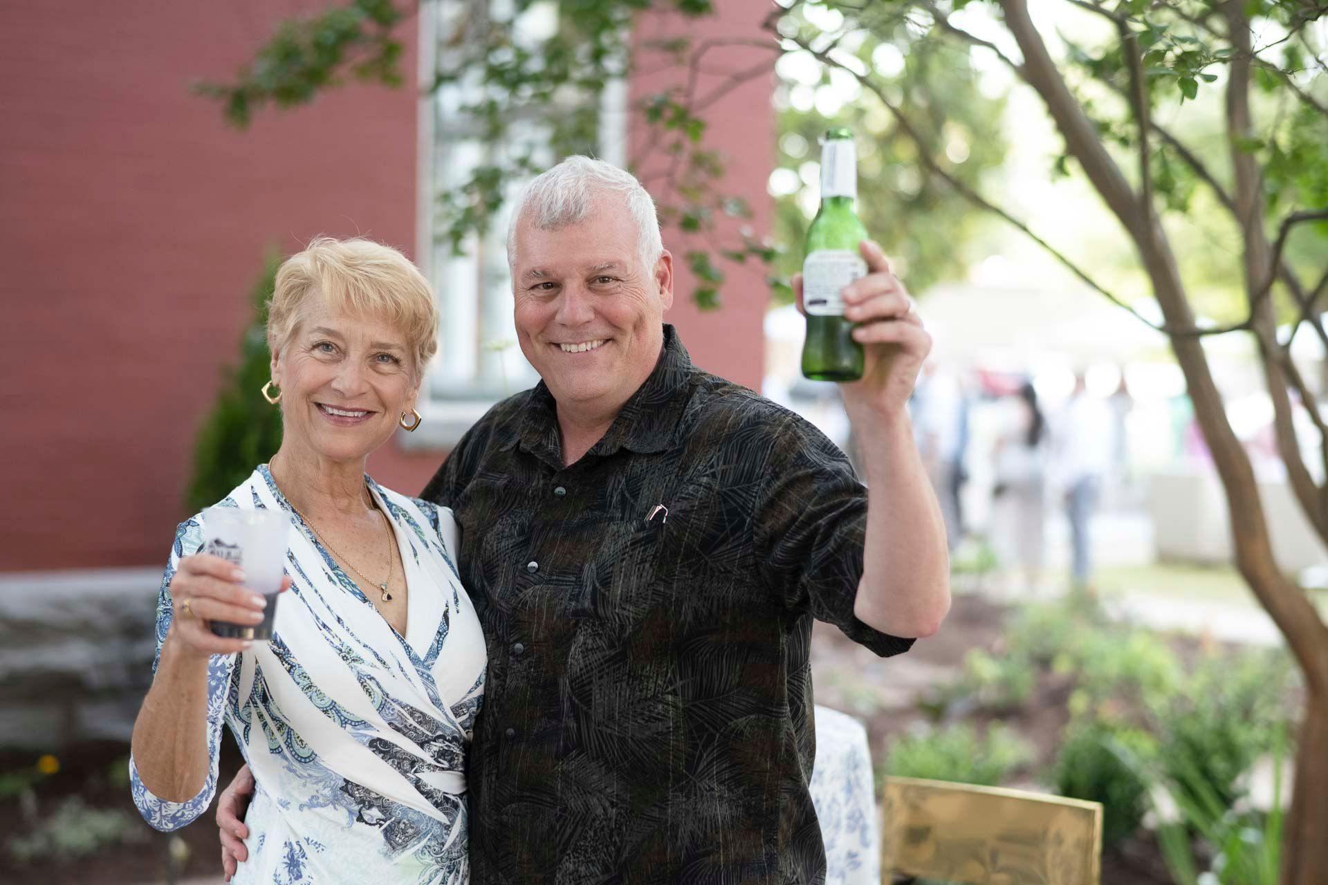 A man and a woman are standing next to each other holding a bottle of wine.