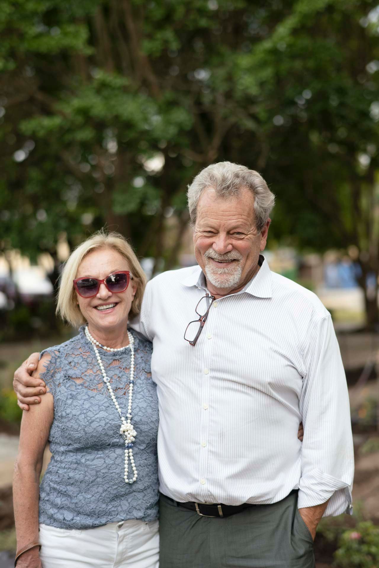 A man and a woman are posing for a picture in a park.