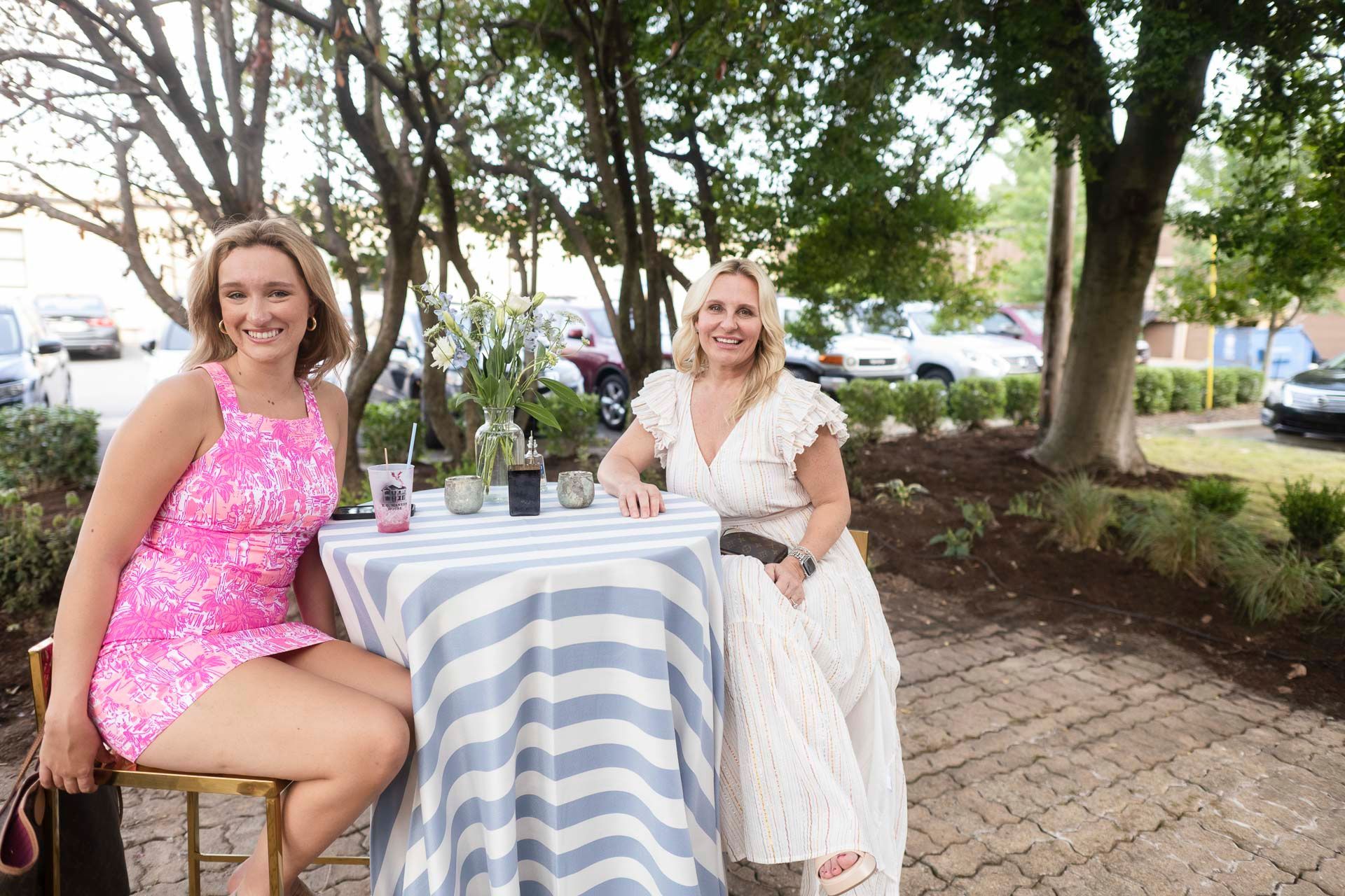 Two women are sitting at a table with a striped tablecloth.