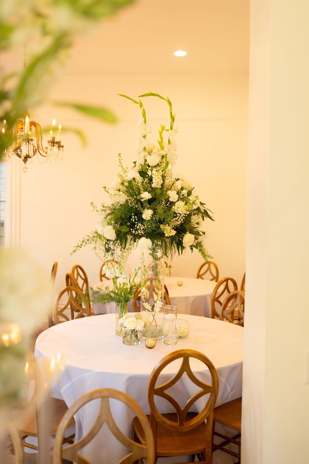 A room with tables and chairs and a vase of flowers on the table.