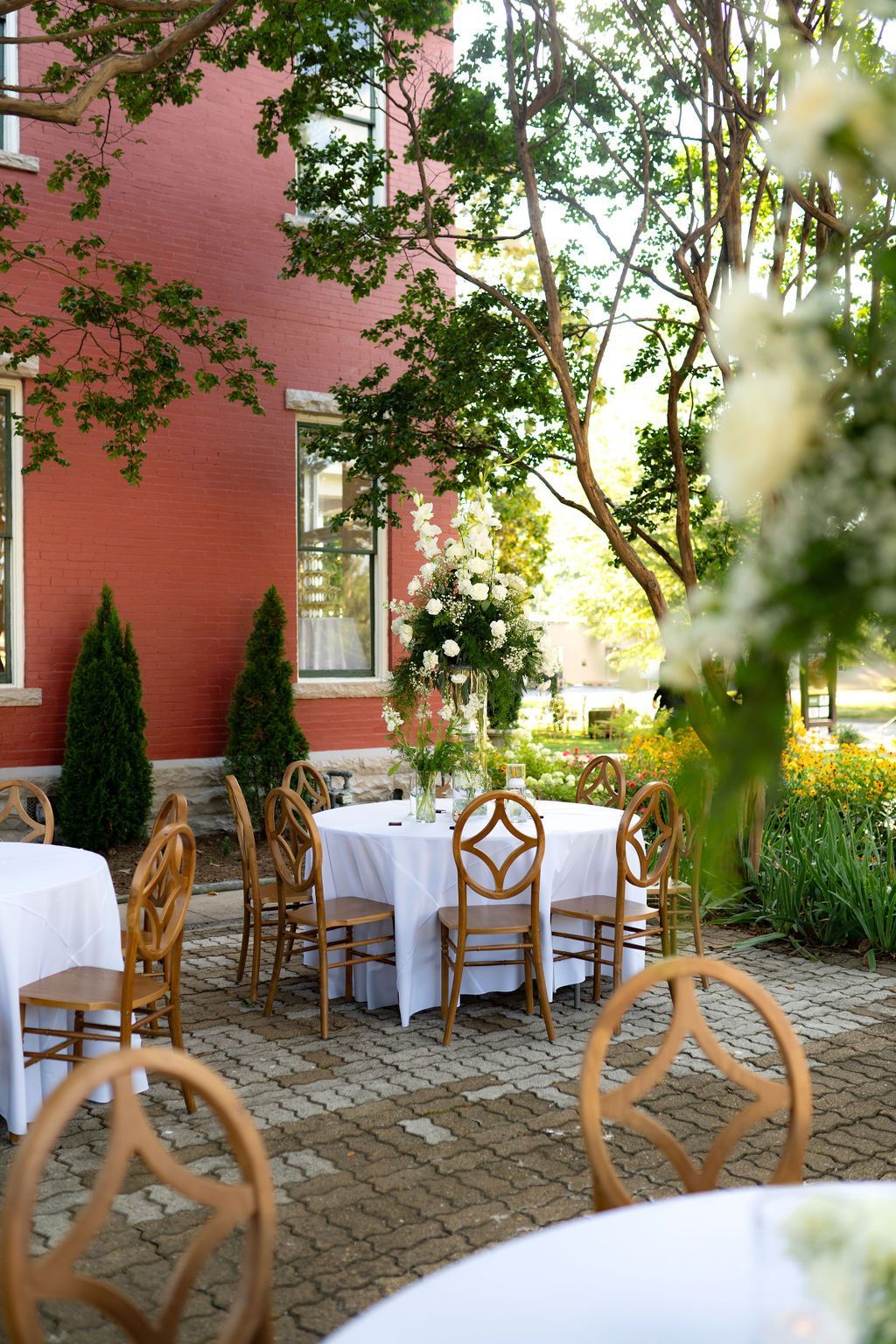 Tables and chairs are set up on a patio in front of E.O. Manees House