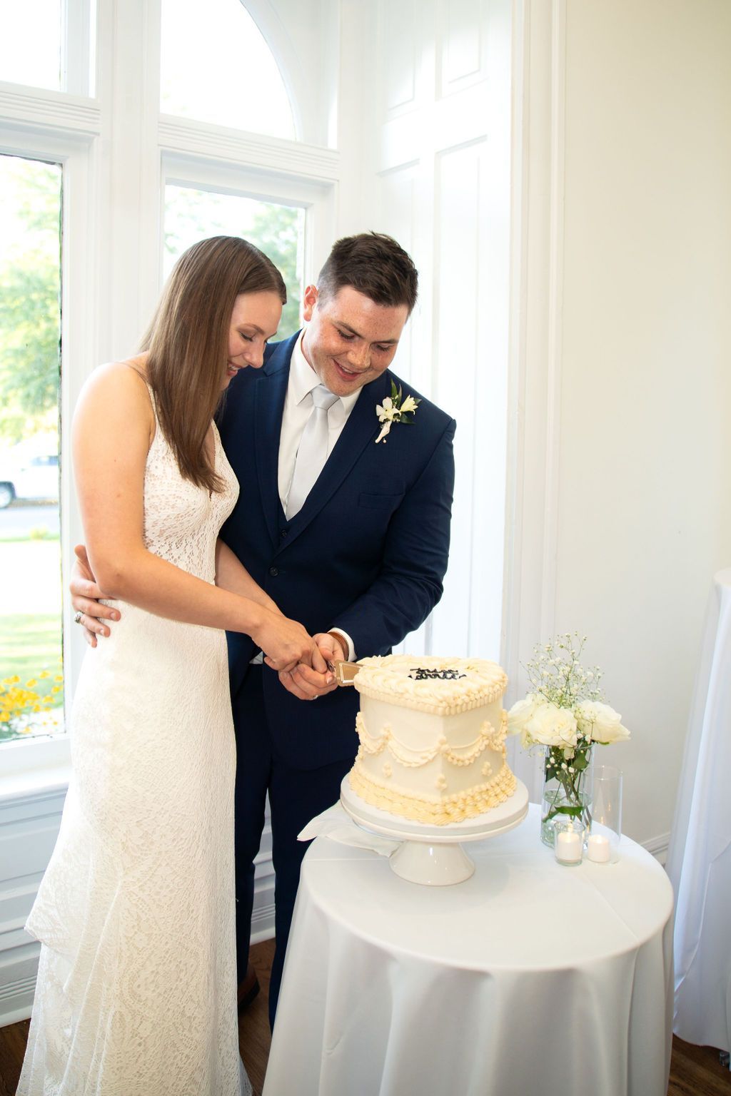 A bride and groom are cutting their wedding cake together.