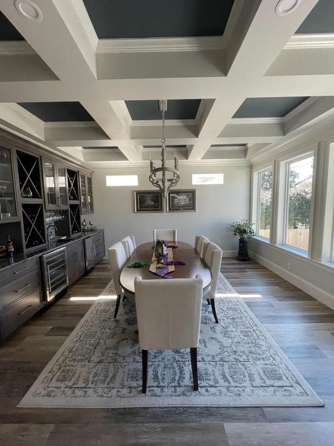 A dining room with a long table and chairs and a coffered ceiling.