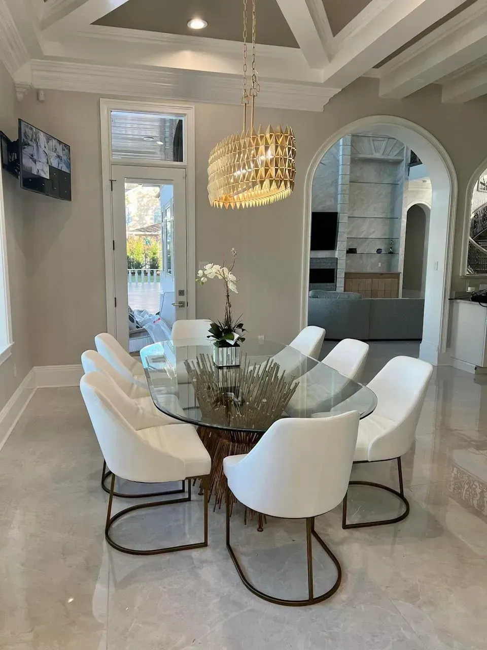 A dining room with a glass table and white chairs
