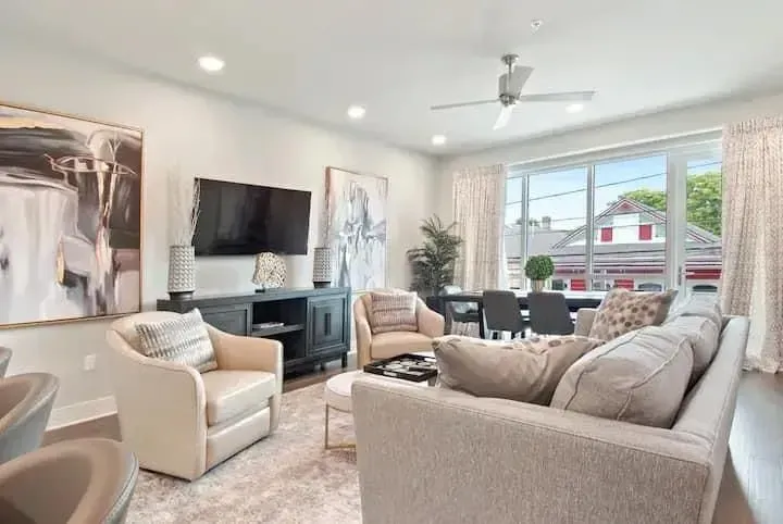 A living room with a couch , chairs , a television and a ceiling fan.