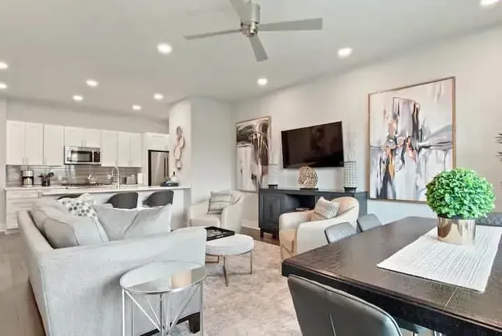 A living room with a couch , table , chairs and a ceiling fan.