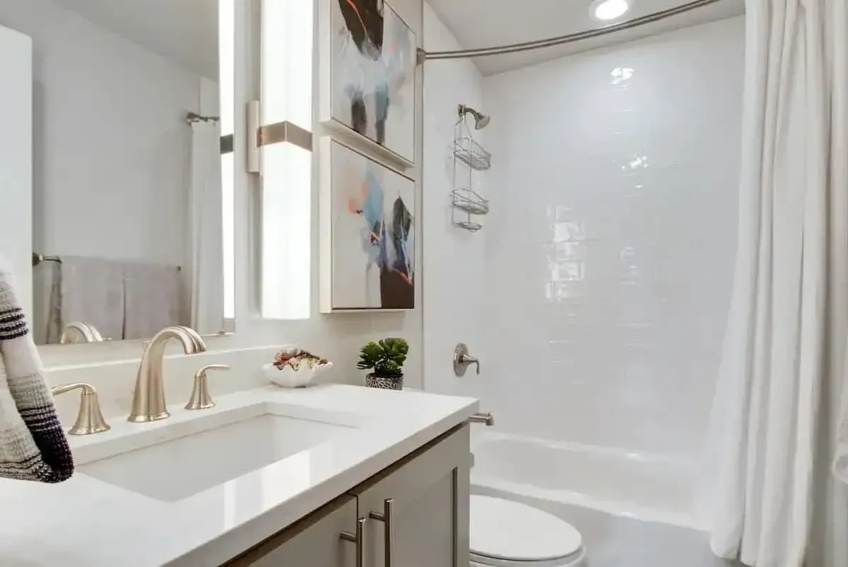 A bathroom with a sink , toilet , shower and mirror.