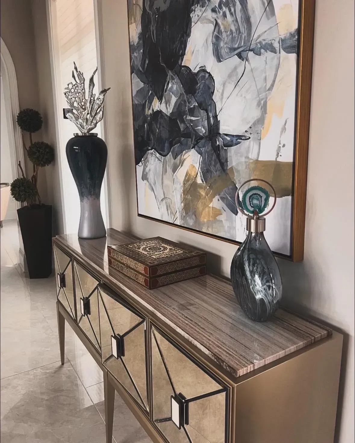 A painting is hanging above a table in a hallway.