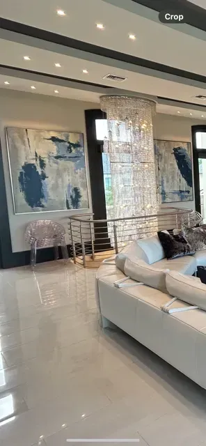 A living room with a couch , stairs , and paintings on the wall.