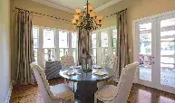 A dining room with a round table and chairs and a chandelier.