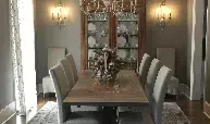 A dining room with a long table and chairs and a chandelier.