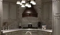 A kitchen with a stove , sink , cabinets and a hood.