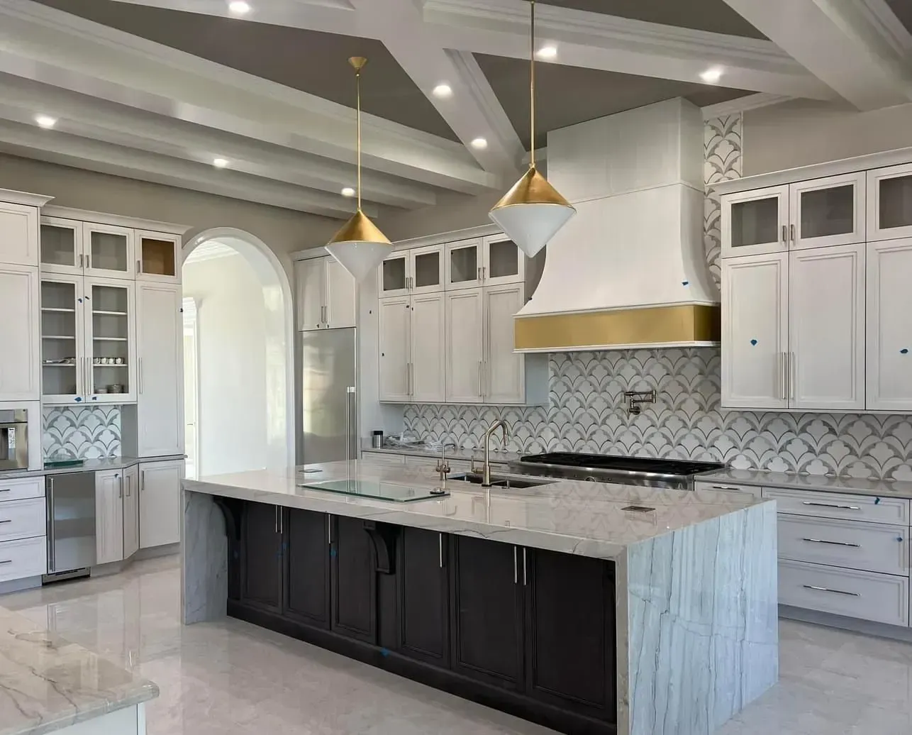 A kitchen with white cabinets , black cabinets , and a large island.