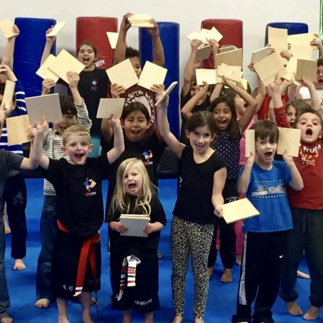 a group of children are posing for a picture with papers in their hands