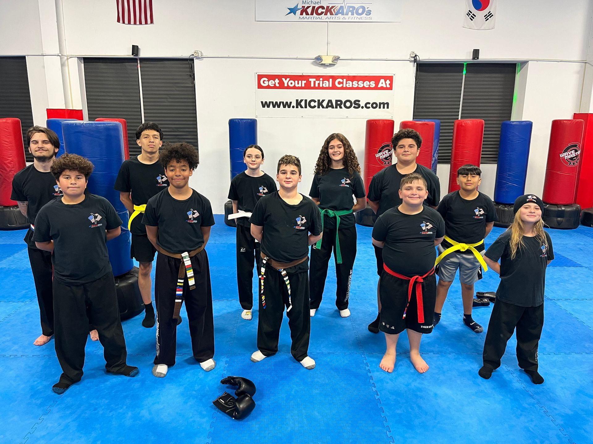 A group of people are posing for a picture in a gym with the word karo on the wall