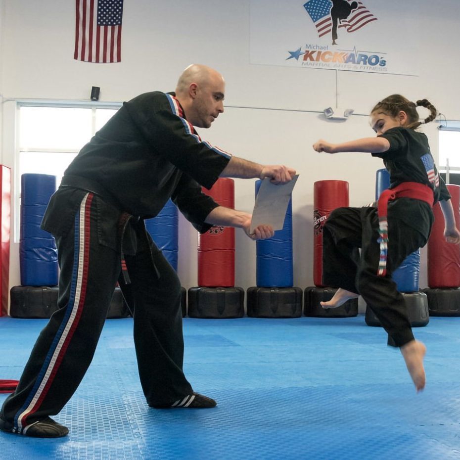 a man and a girl are practicing martial arts in front of a sign that says kickaro