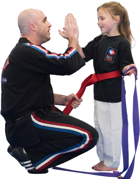 a man high fives a little girl who is wearing a red belt