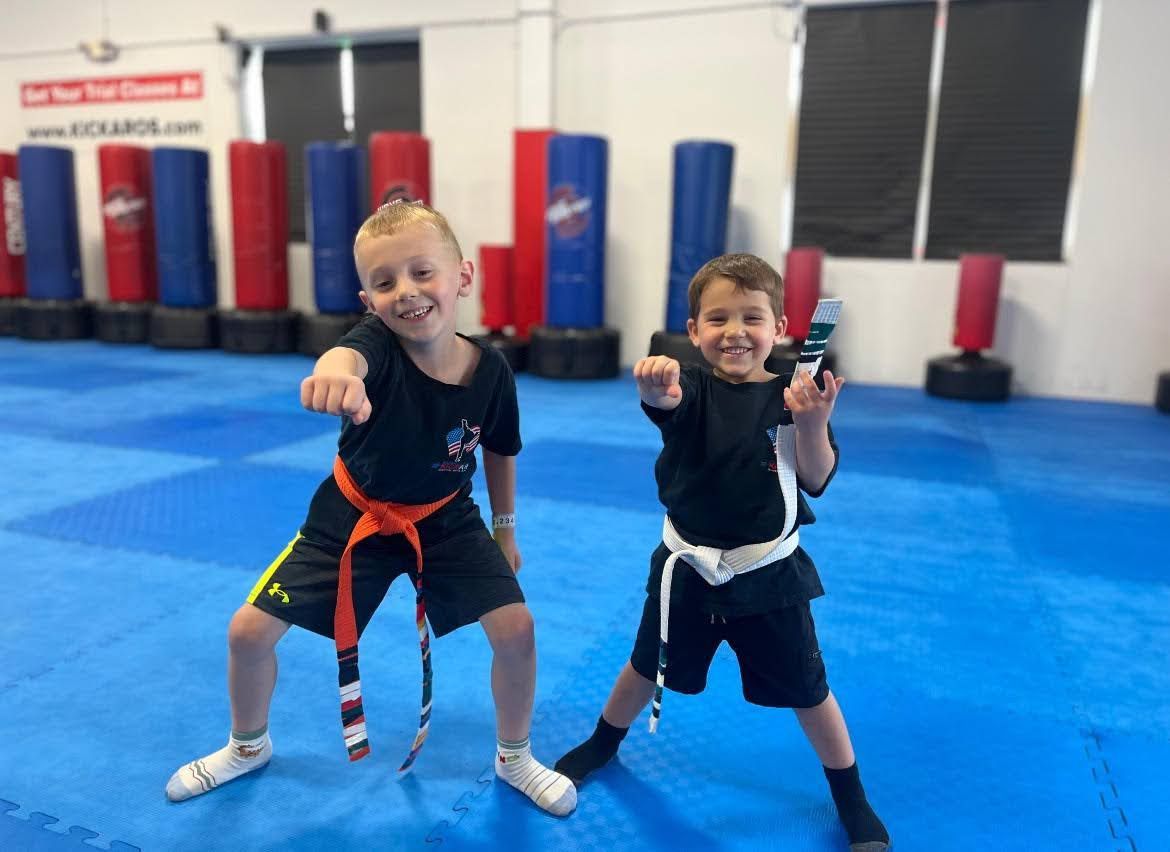 A young boy wearing a black shirt and a blue belt giving a thumbs up