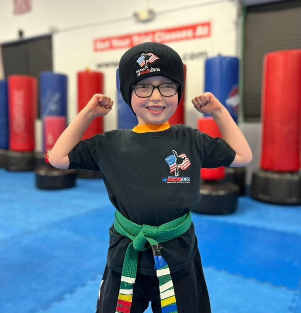 A young boy flexing his muscles in a gym