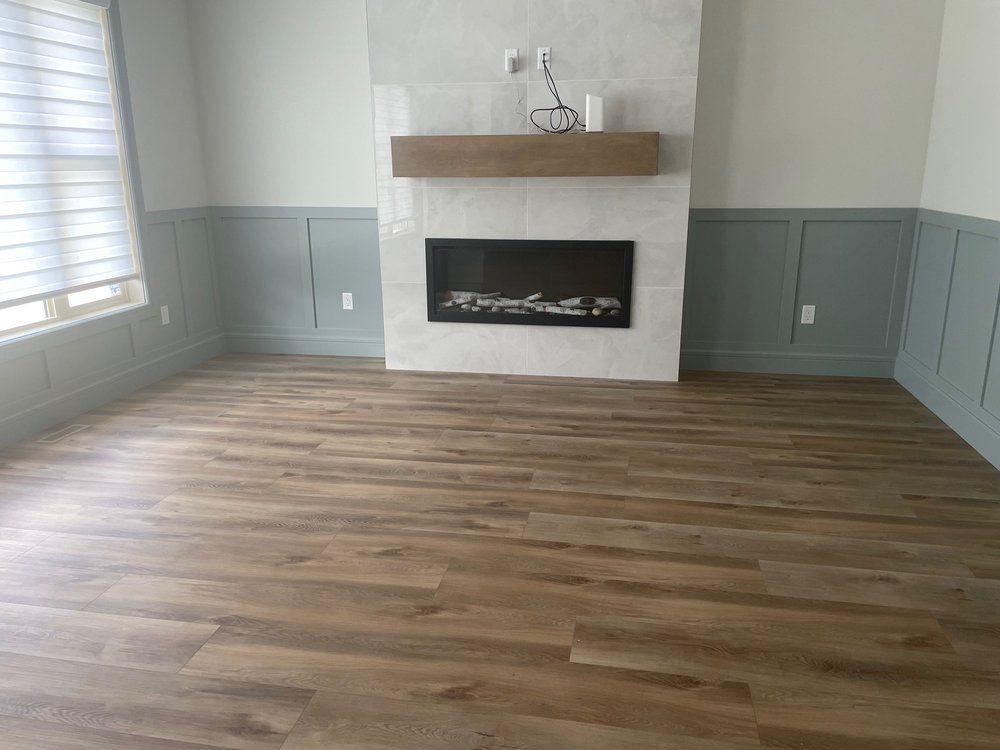 Luxury vinyl plank flooring installed in Sherwood Park living room with tile fireplace surround by XMP Construction.