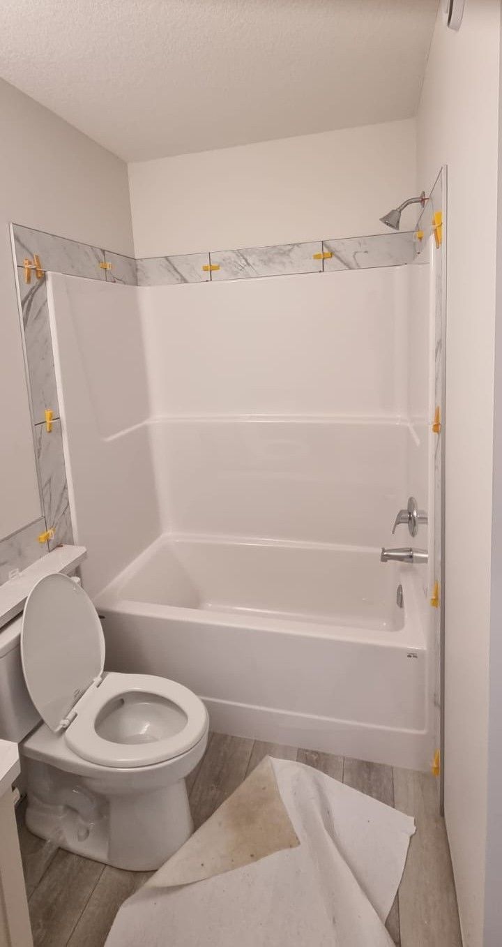 Installation of elegant white marble-look tiles around a bathtub in a Sherwood Park bathroom by XMP Construction.