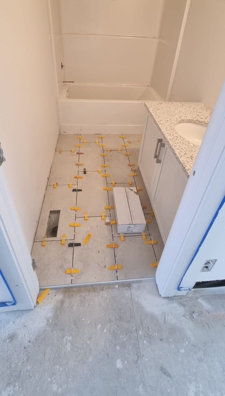 Installation of light grey floor tiles in a Sherwood Park bathroom by XMP Construction.