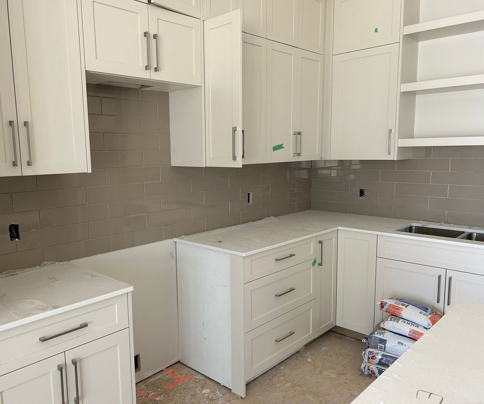 Modern Sherwood Park kitchen with white cabinets, countertops, and a grey subway tile backsplash by XMP Construction.