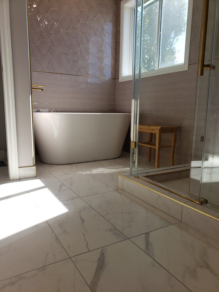 Bright Sherwood Park bathroom with a freestanding tub and stylish grey tiles by XMP Construction.