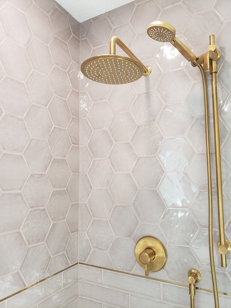Stylish Sherwood Park shower featuring grey hexagon and white subway tiles with gold fixtures by XMP Construction.