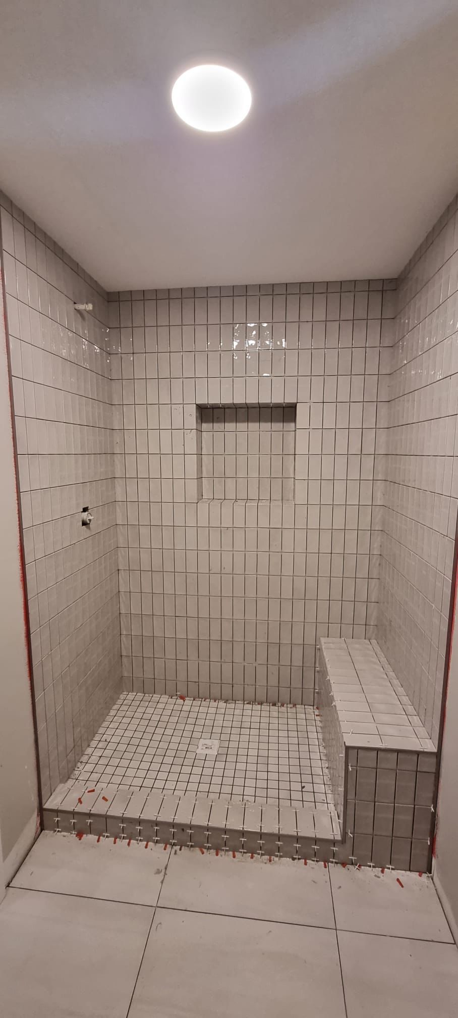 Installation of light grey square shower tiles with a bench in Sherwood Park by XMP Construction.