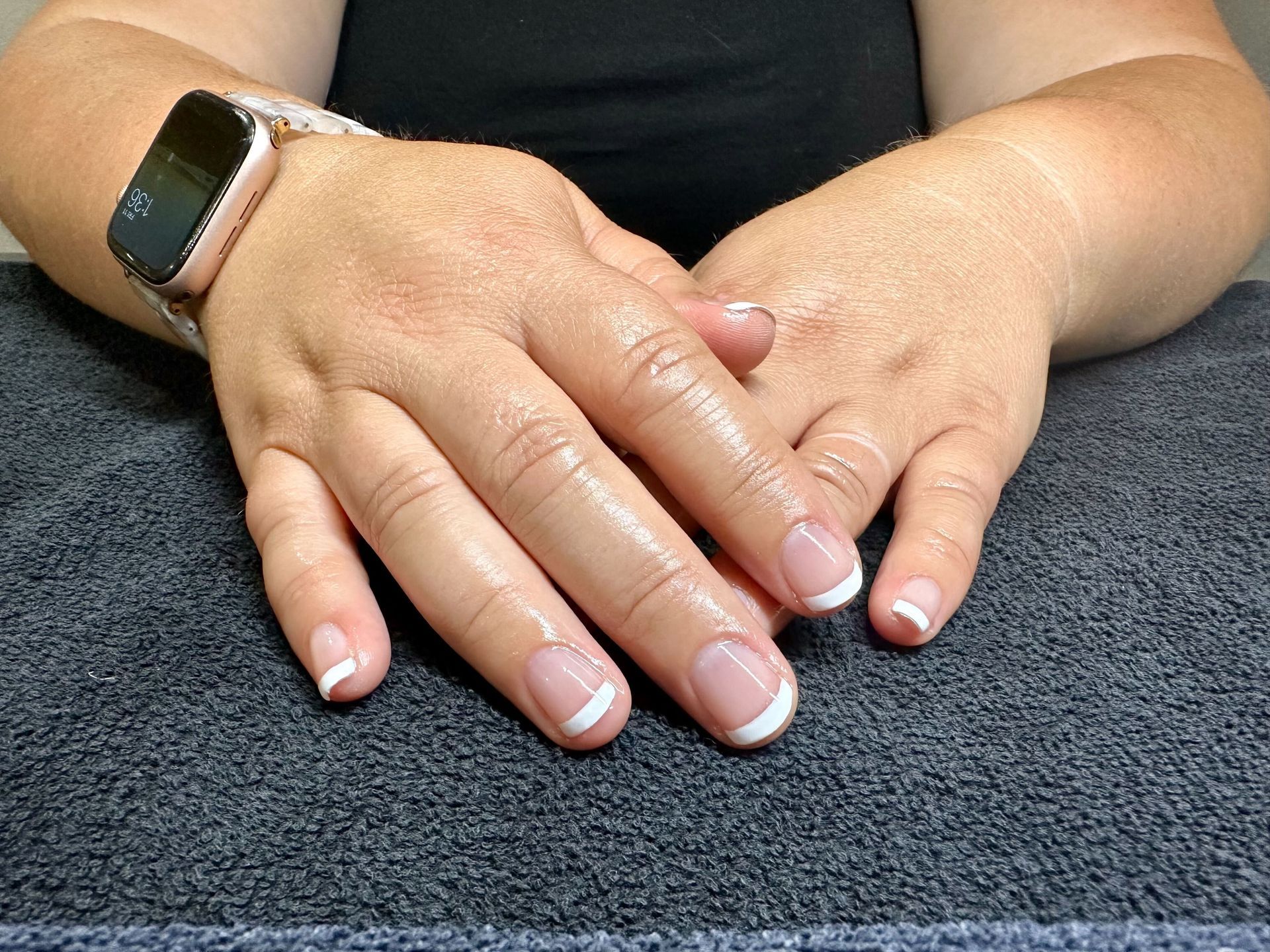 a woman wearing a fitbit watch has her hands folded