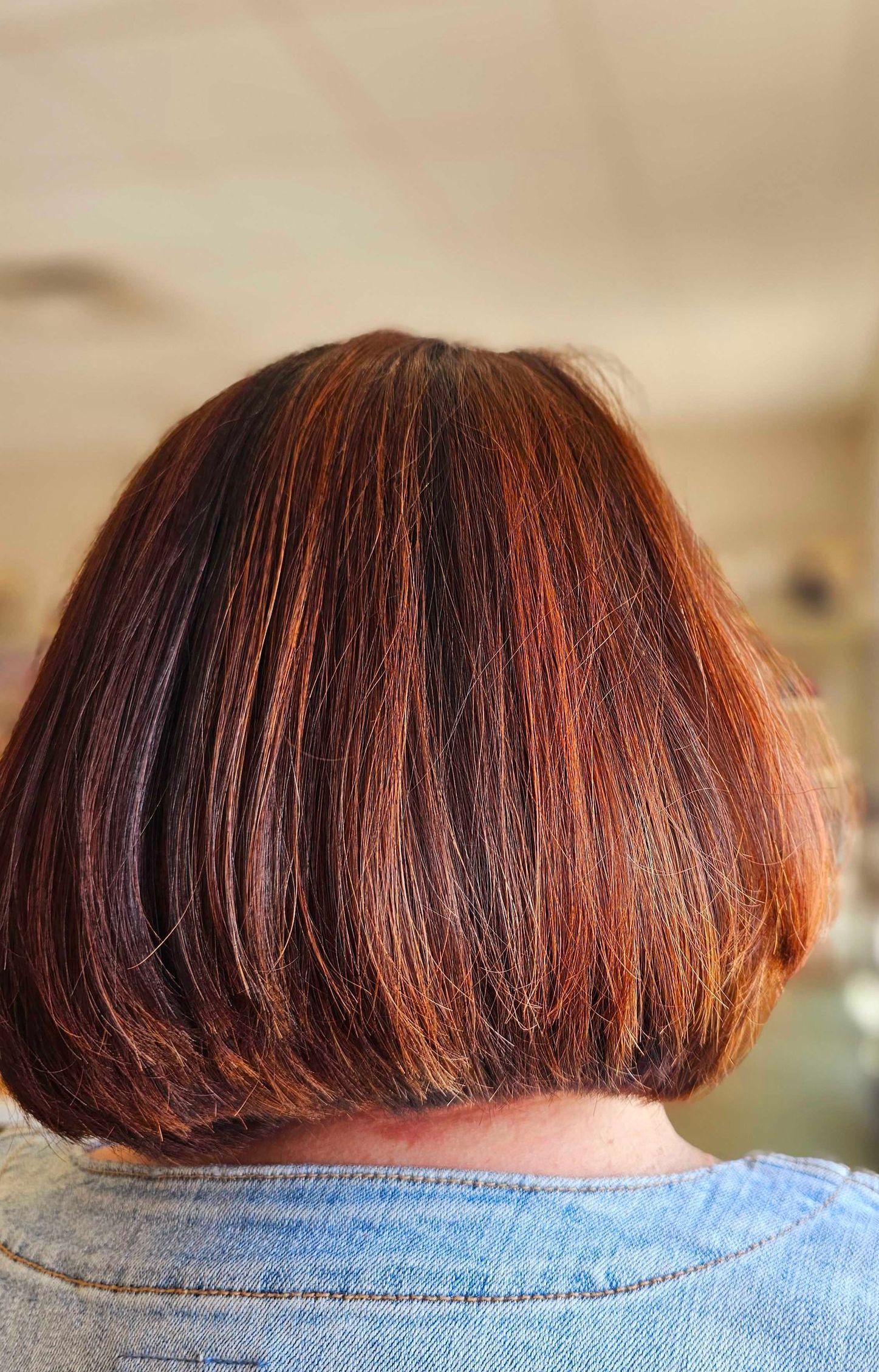 a woman with short red hair is wearing a blue denim shirt
