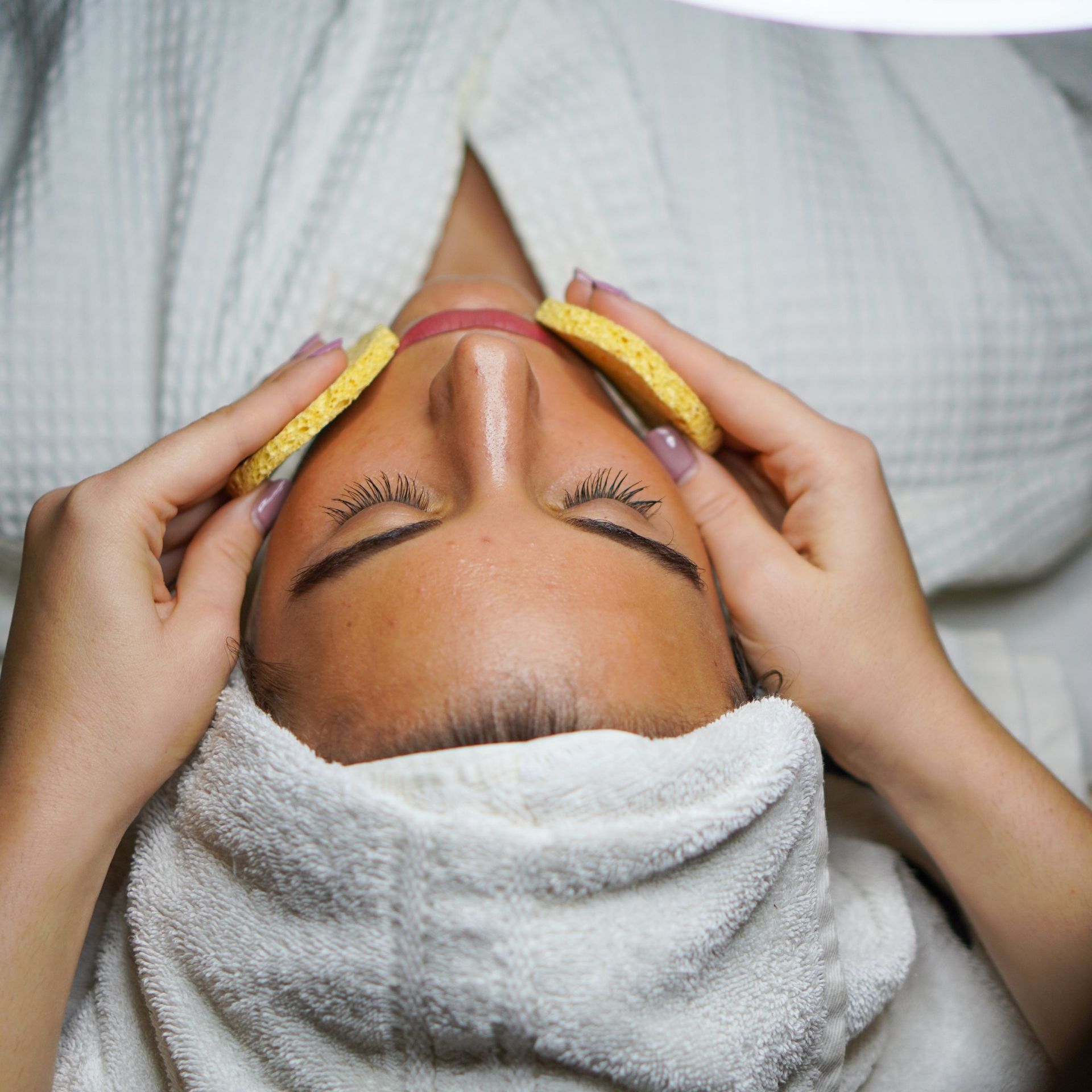 a woman with a towel wrapped around her head is getting a facial treatment