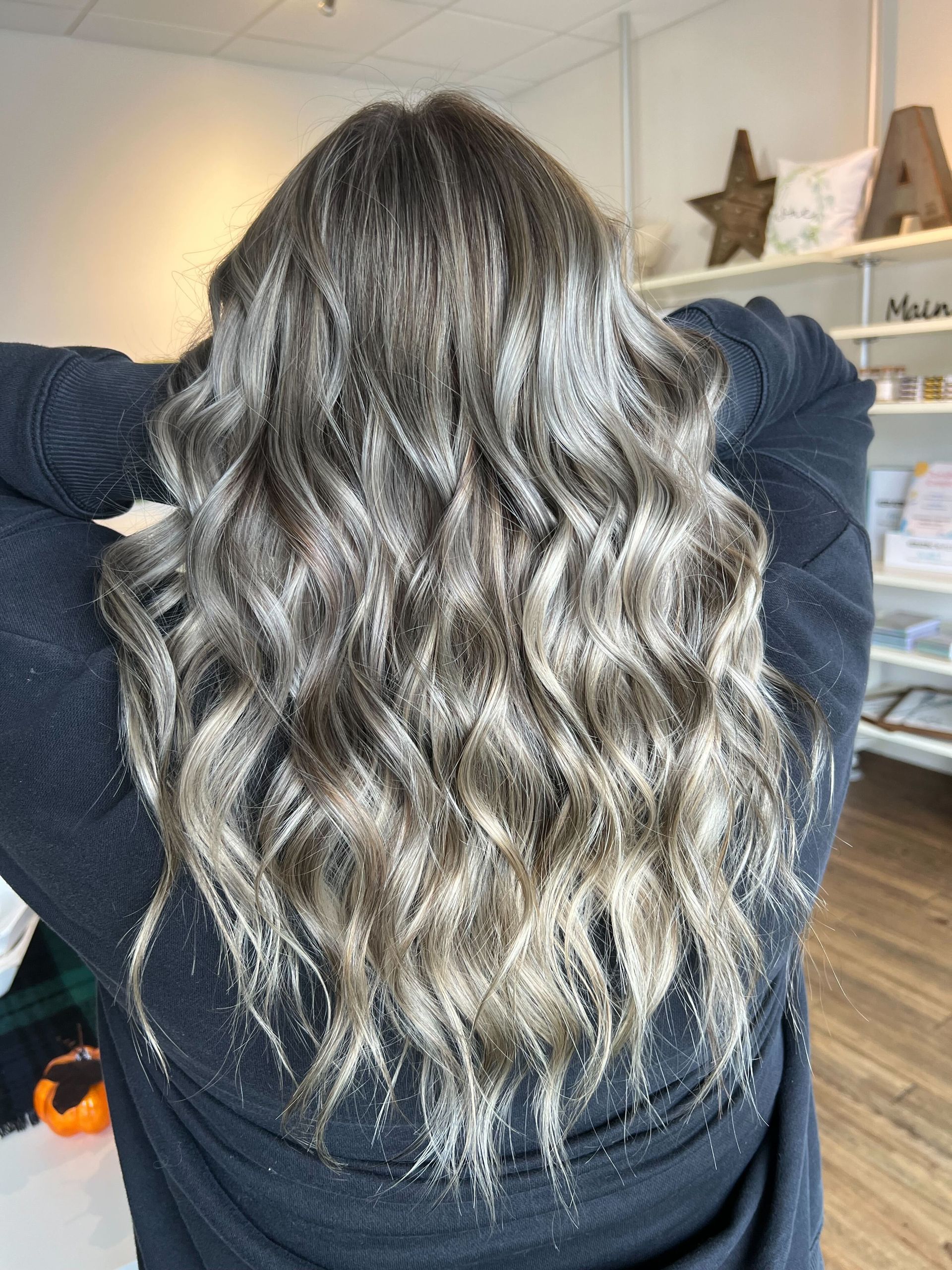 a woman wearing a black sweater has her hands behind her head showing off her new hair