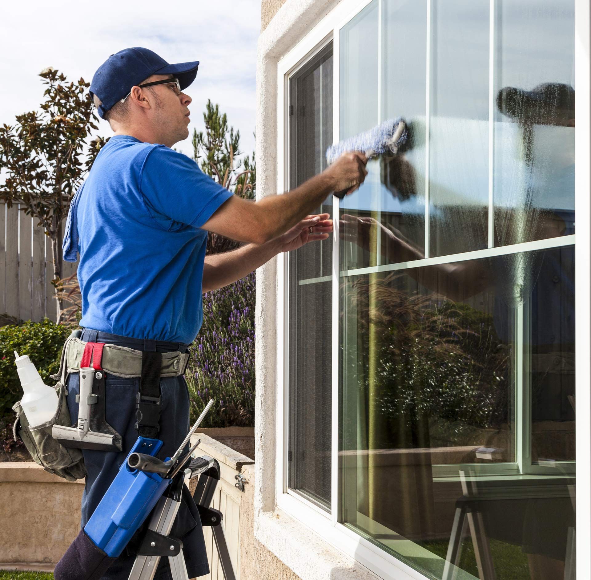 A man in a blue shirt is cleaning a window with a brush