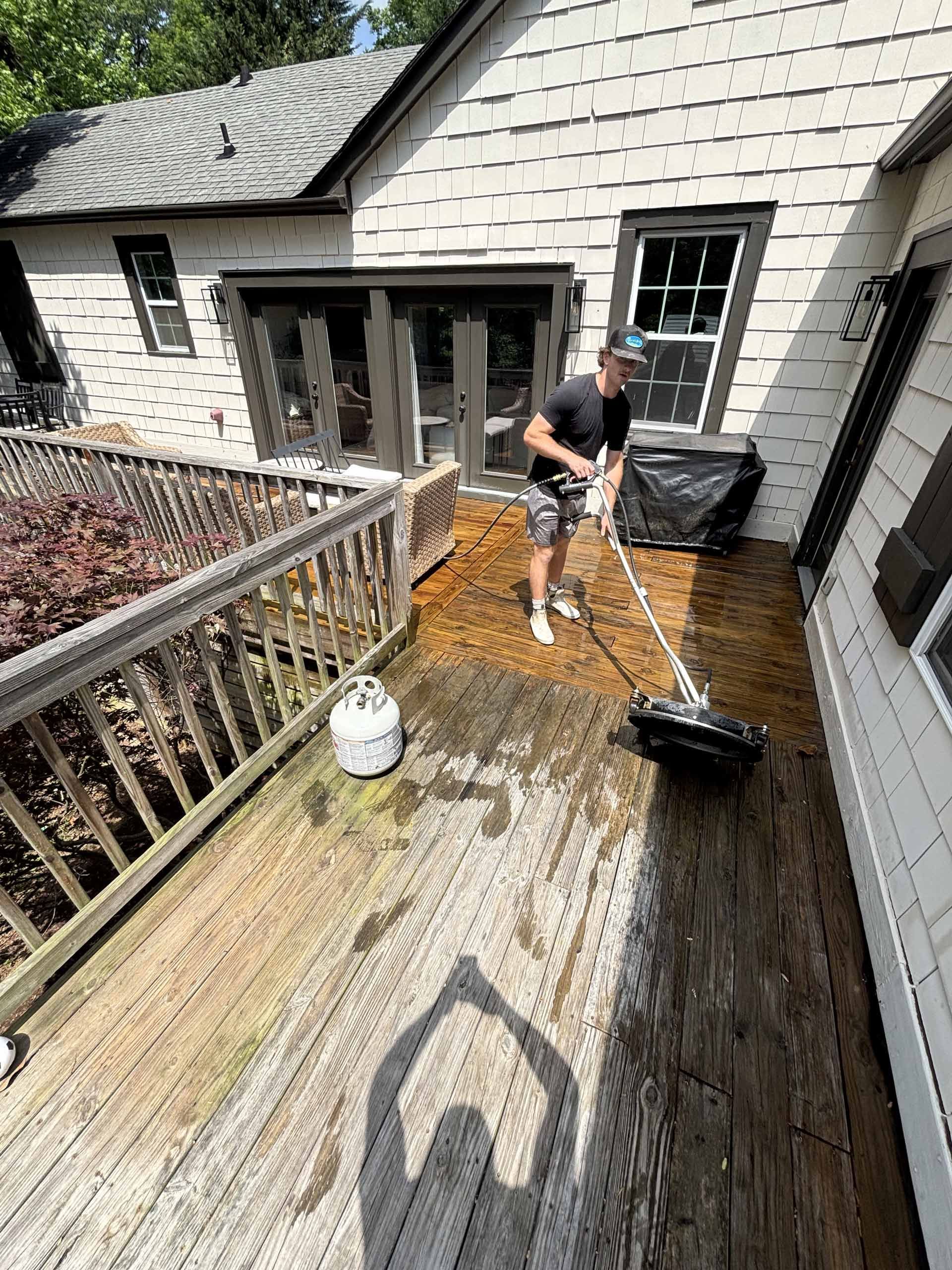 A man is cleaning a wooden deck with a broom.