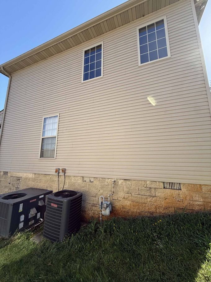 The back of a house with two air conditioners in the backyard.