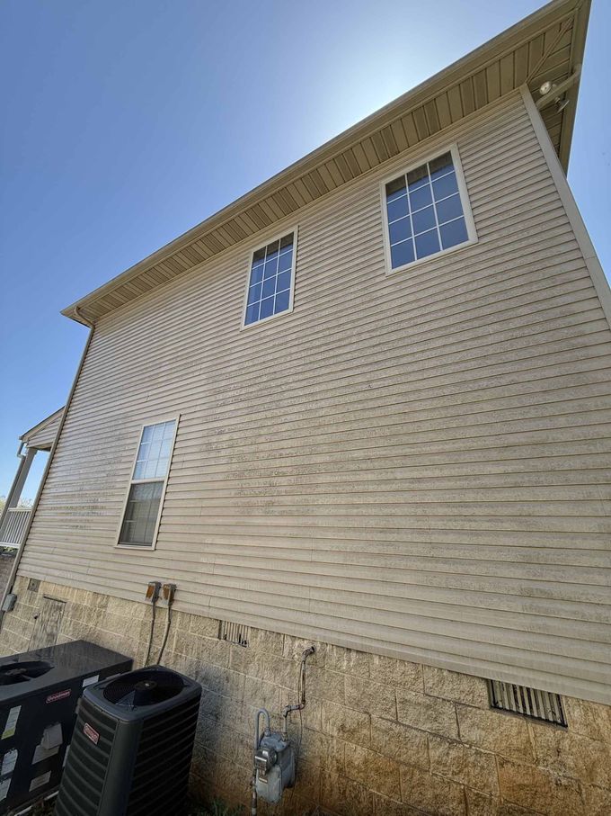 A house with a lot of windows and an air conditioner on the side of it.