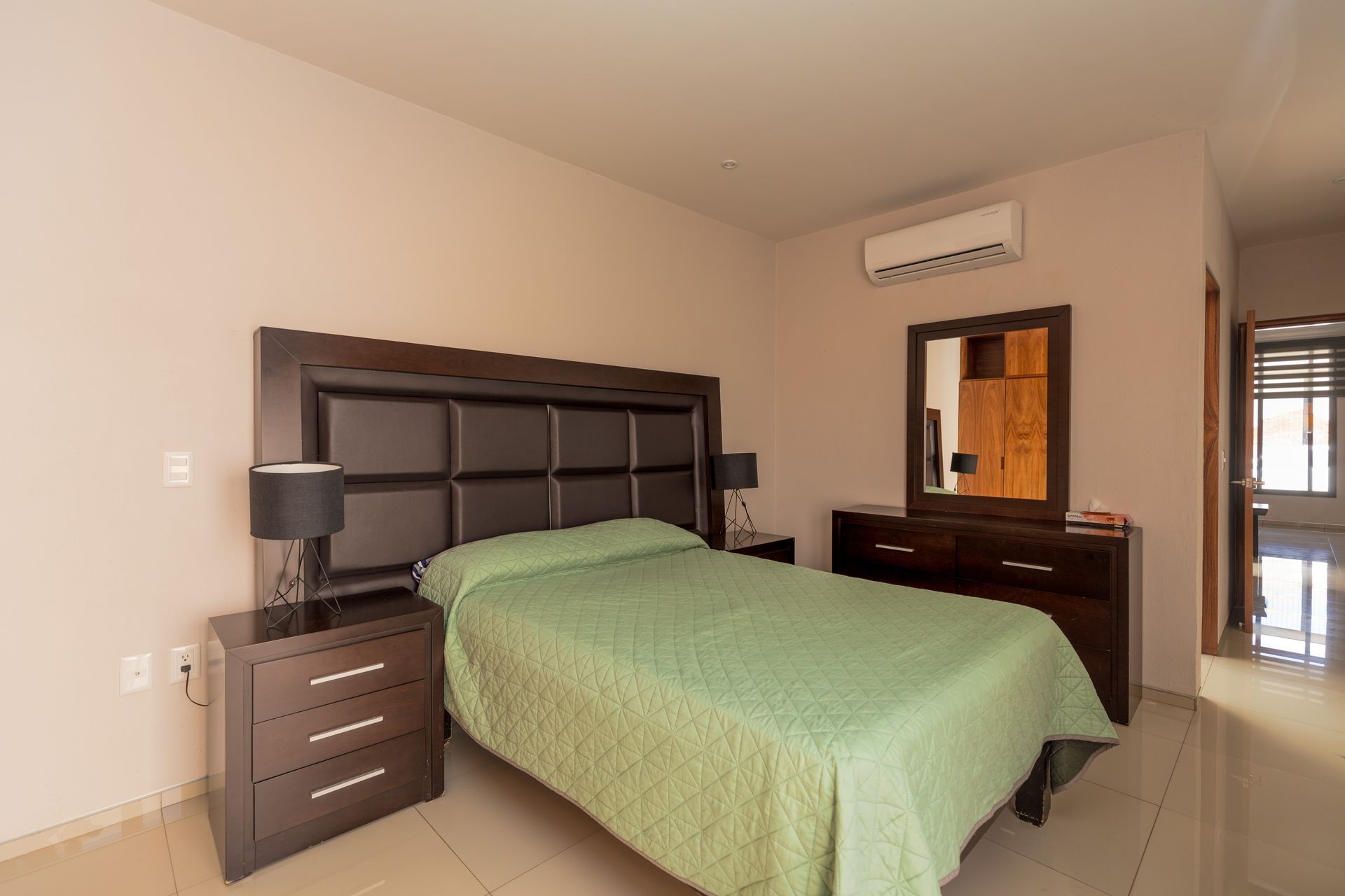 a bedroom with a bed , nightstand , mirror and dresser .