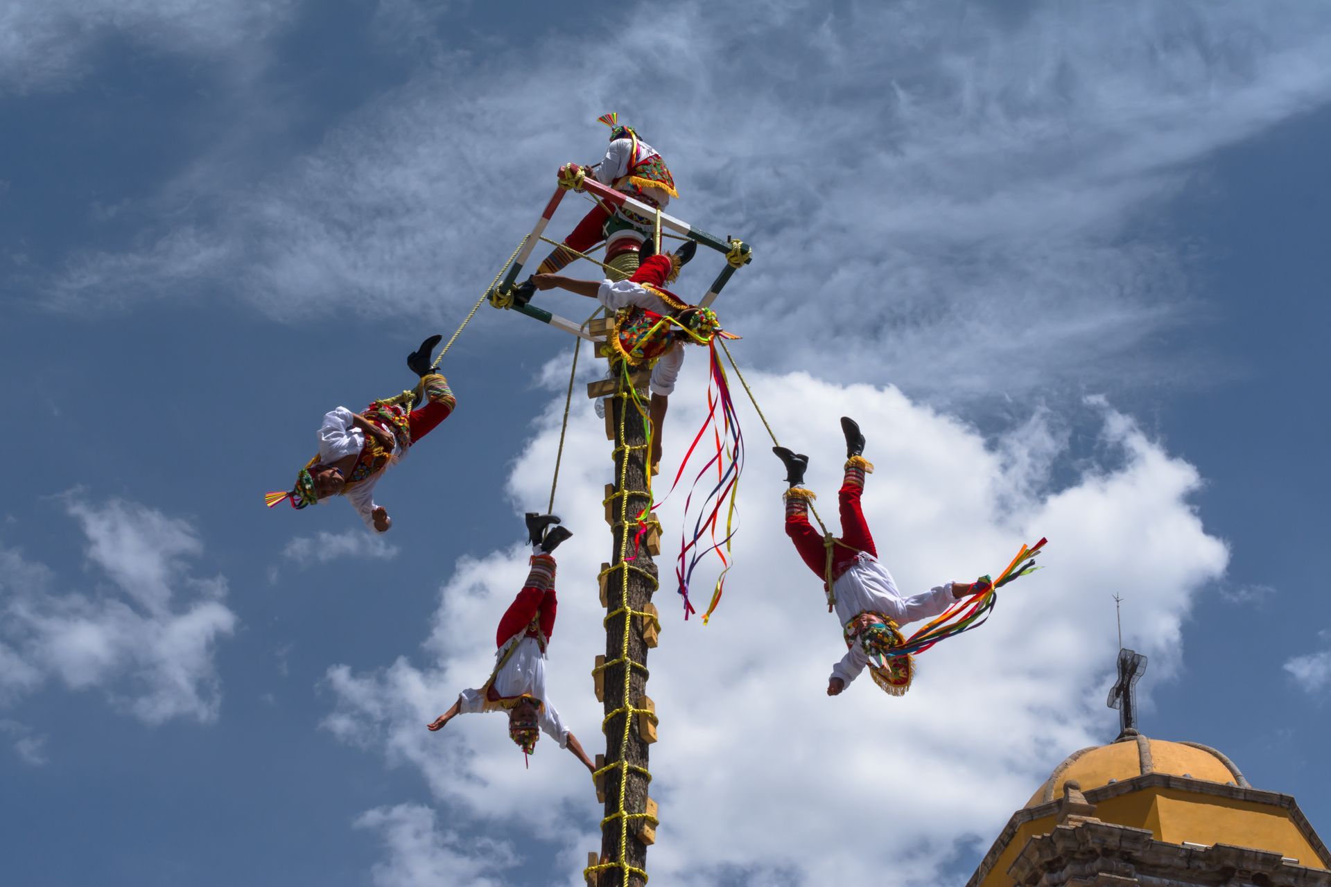 a group of people are hanging from a pole in the air .