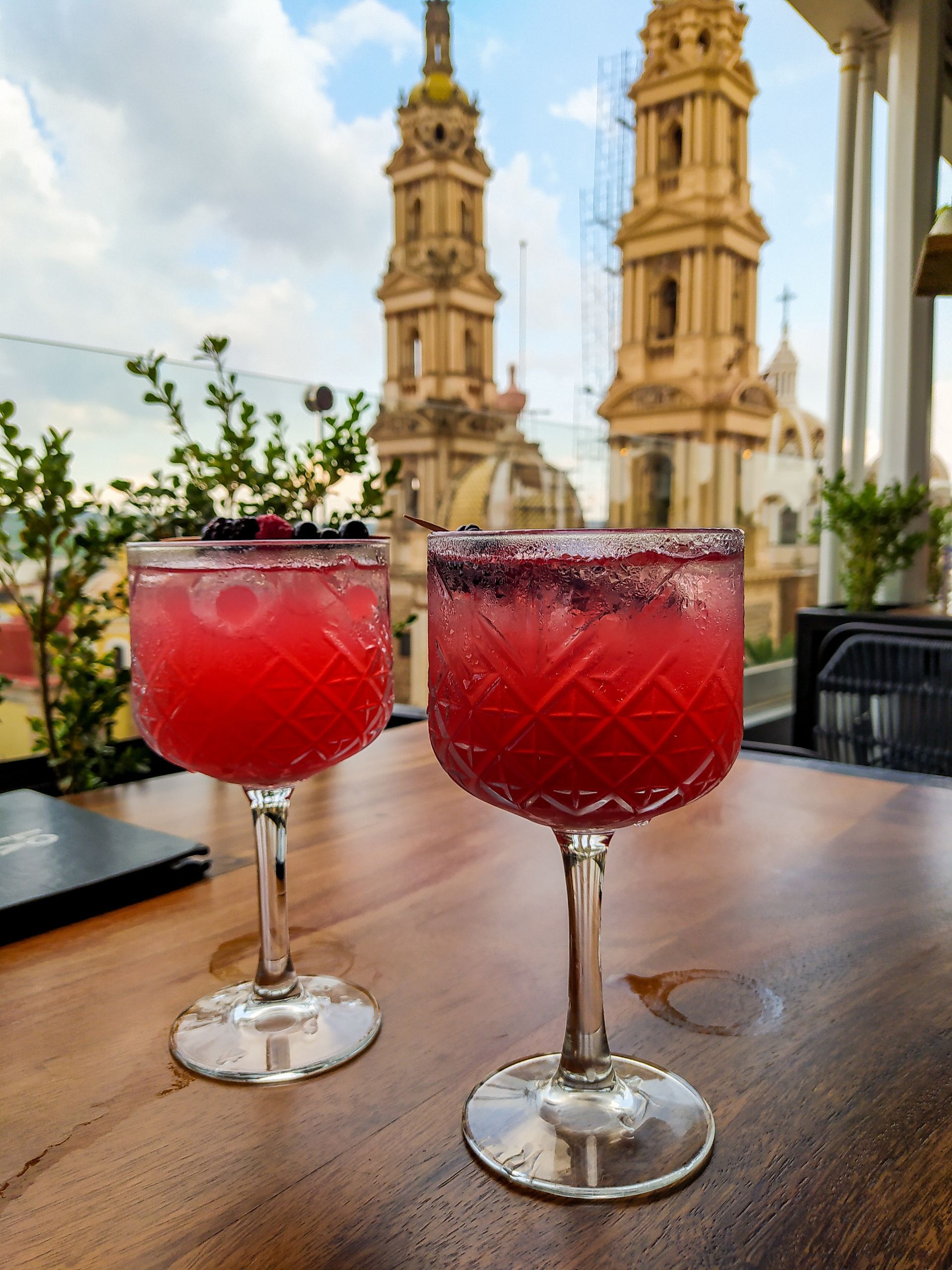 two glasses of red liquid are sitting on a wooden table .