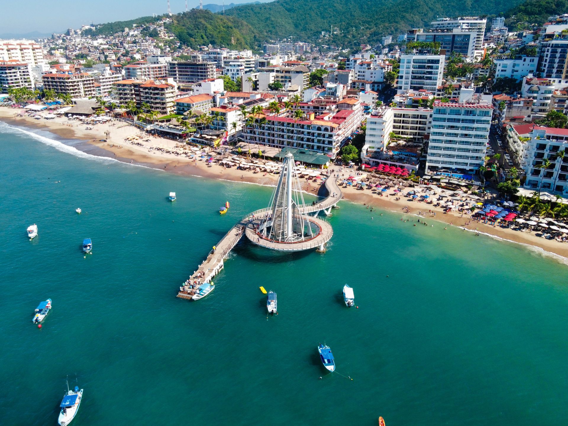 an aerial view of a beach with a pier and boats in the water .