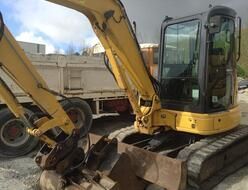 A yellow excavator is parked next to a dump truck.