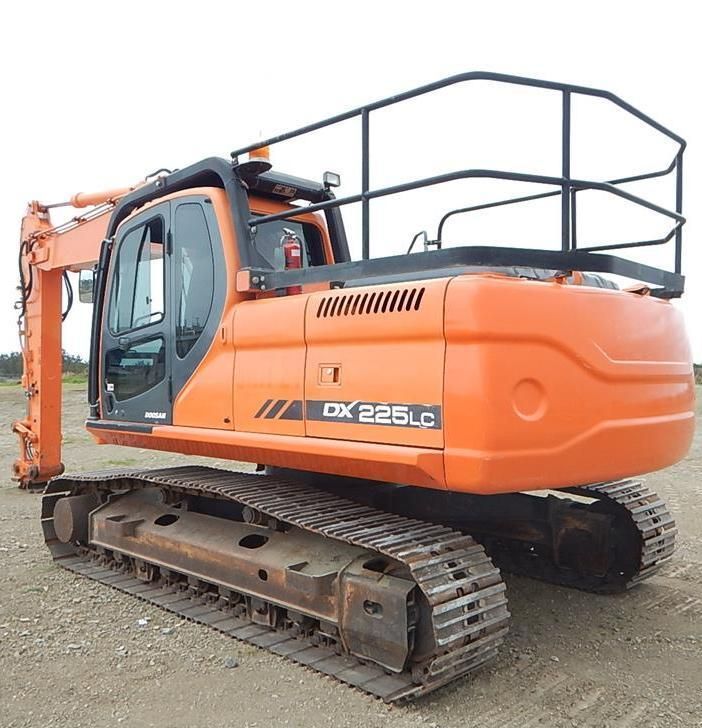 A large orange excavator is parked in a dirt field